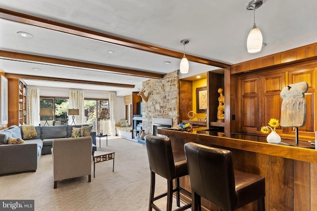 interior space featuring a stone fireplace, light carpet, beamed ceiling, and hanging light fixtures