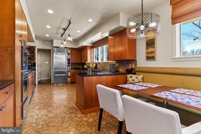 kitchen featuring dark countertops, brown cabinetry, a peninsula, and stainless steel appliances