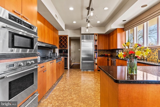 kitchen featuring visible vents, appliances with stainless steel finishes, brown cabinetry, and decorative backsplash