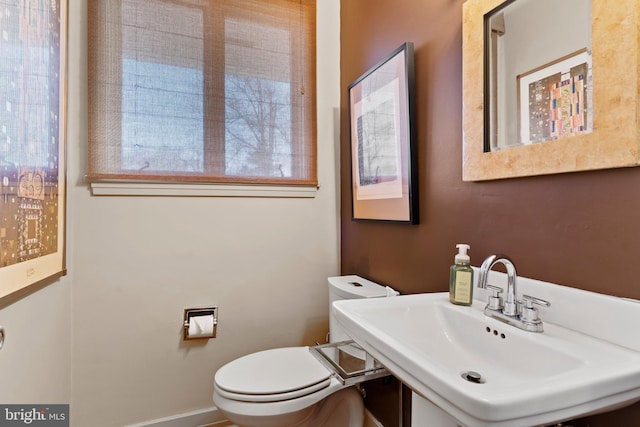 half bath with a sink, toilet, and baseboards