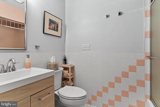 bathroom featuring toilet, wainscoting, tile walls, and vanity