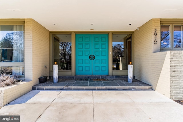 entrance to property featuring a patio area and brick siding