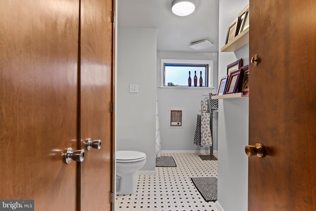 bathroom with baseboards, toilet, and tile patterned floors