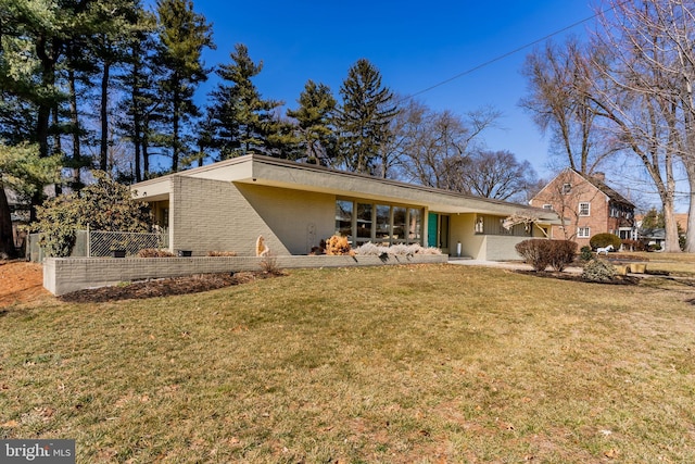 rear view of property with a lawn and brick siding