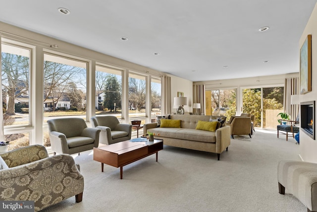 living area featuring carpet, a healthy amount of sunlight, a multi sided fireplace, and recessed lighting