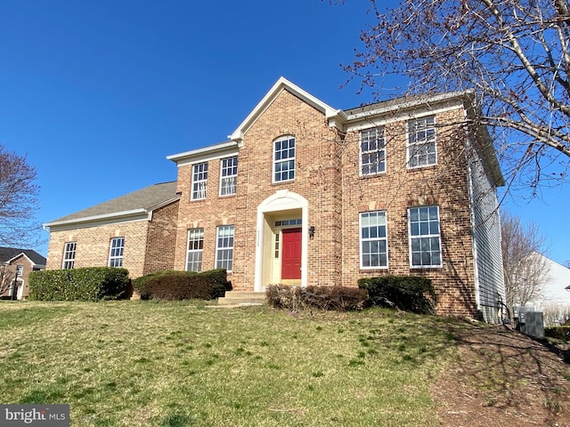 colonial home with brick siding, central AC, and a front lawn