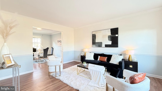 living area with baseboards, wood finished floors, and crown molding