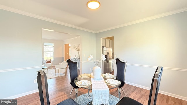 dining space featuring light wood-type flooring, baseboards, and crown molding