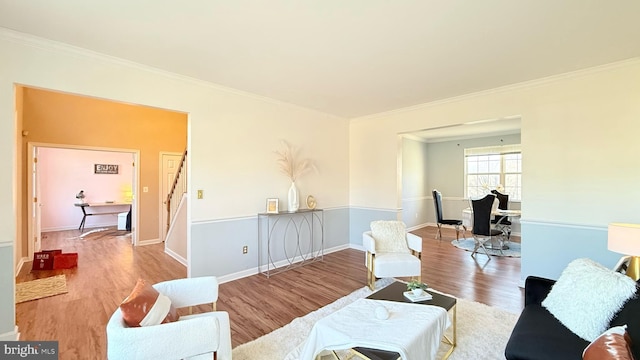 living area with stairs, crown molding, wood finished floors, and baseboards