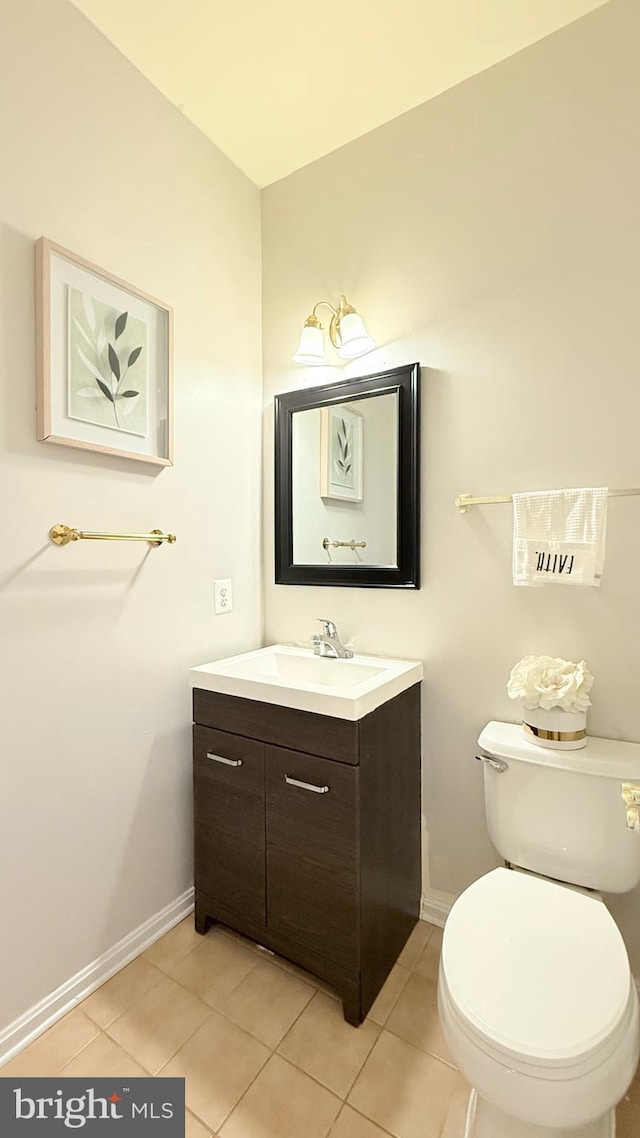 half bath with tile patterned floors, toilet, vanity, and baseboards