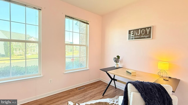 office space with visible vents, plenty of natural light, baseboards, and wood finished floors