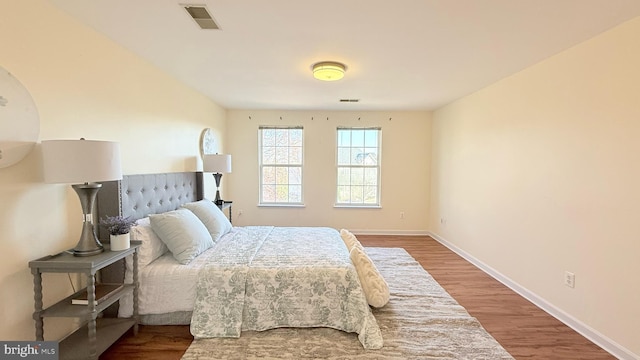 bedroom with visible vents, baseboards, and wood finished floors