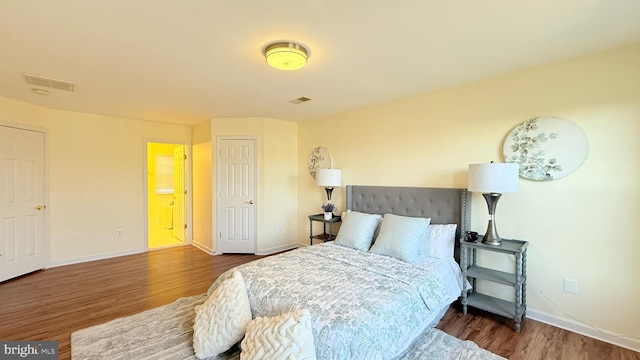 bedroom with visible vents, baseboards, and wood finished floors