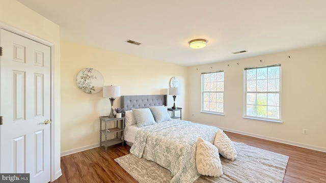 bedroom featuring wood finished floors, visible vents, and baseboards