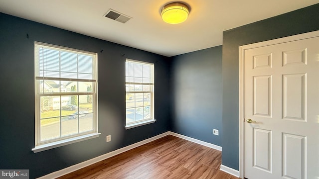 empty room featuring visible vents, baseboards, and wood finished floors