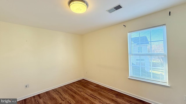 unfurnished room featuring visible vents, baseboards, and dark wood-type flooring