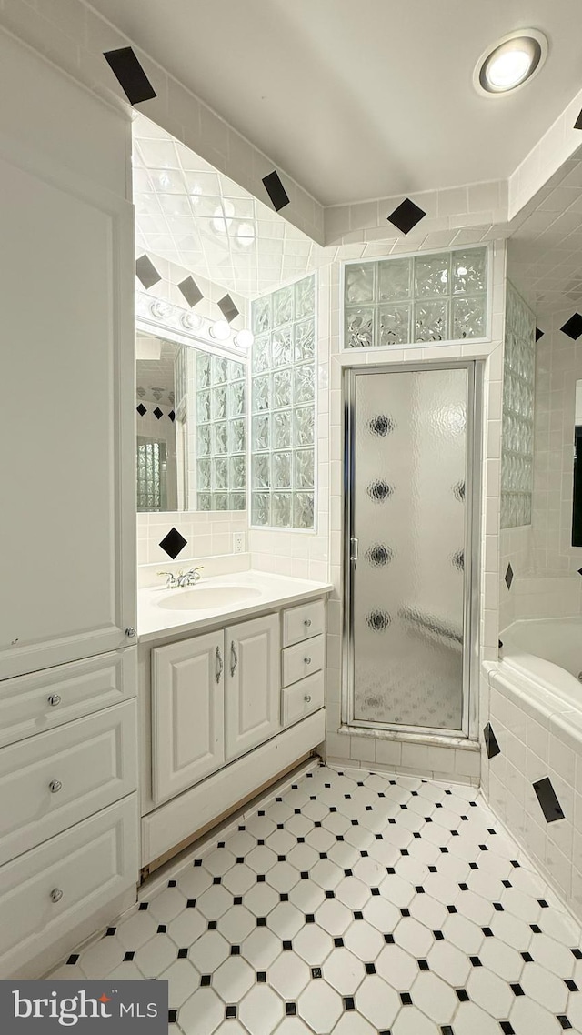 bathroom featuring tile patterned floors, a shower stall, vanity, and a relaxing tiled tub