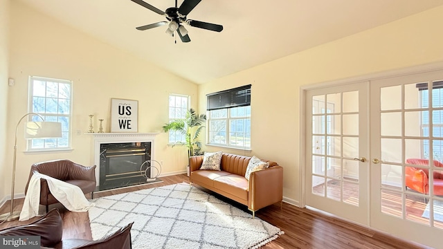 sitting room with wood finished floors, baseboards, lofted ceiling, a fireplace with flush hearth, and french doors