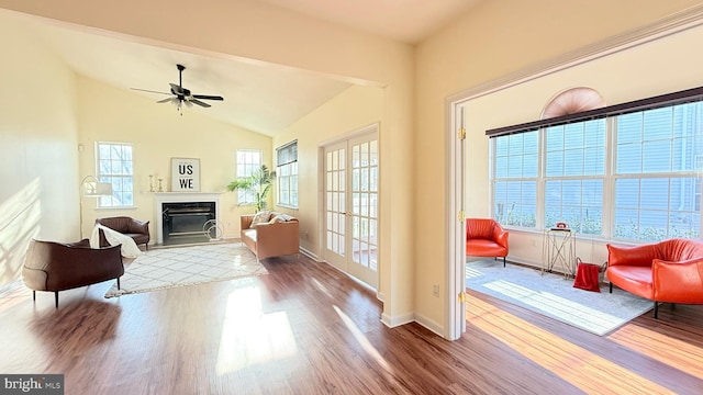 sitting room featuring a glass covered fireplace, vaulted ceiling, wood finished floors, and baseboards