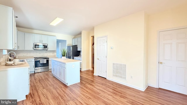 kitchen with visible vents, light countertops, decorative backsplash, appliances with stainless steel finishes, and a sink