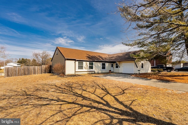 ranch-style house featuring a garage, driveway, and fence