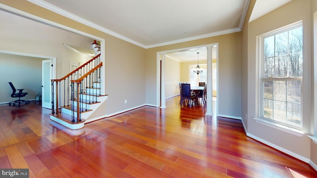 interior space with wood finished floors, baseboards, stairs, crown molding, and a notable chandelier