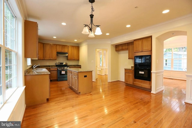 kitchen with a center island, crown molding, brown cabinetry, light wood-style floors, and black appliances