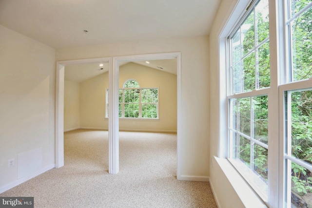 empty room with carpet floors, baseboards, and vaulted ceiling