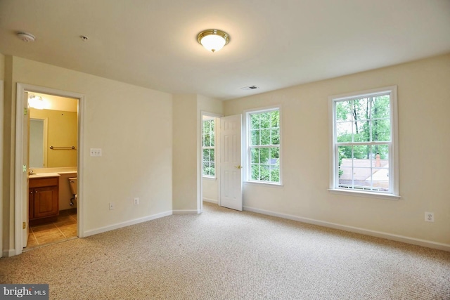 spare room featuring light carpet, visible vents, and baseboards