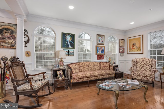 sitting room with ornamental molding, hardwood / wood-style flooring, wainscoting, and decorative columns