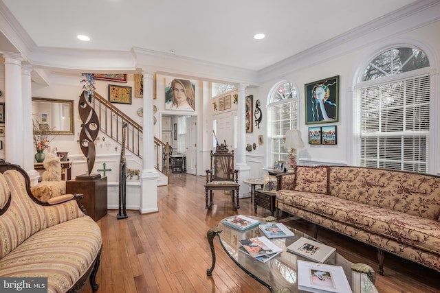 living room featuring ornamental molding, wood-type flooring, stairway, and ornate columns