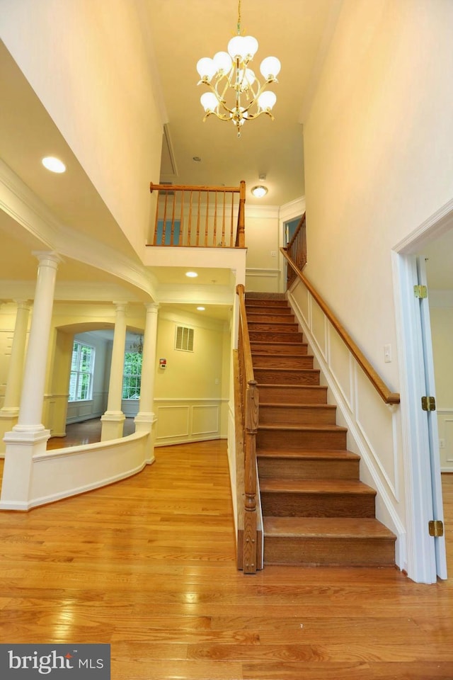 staircase featuring visible vents, ornamental molding, decorative columns, and a decorative wall