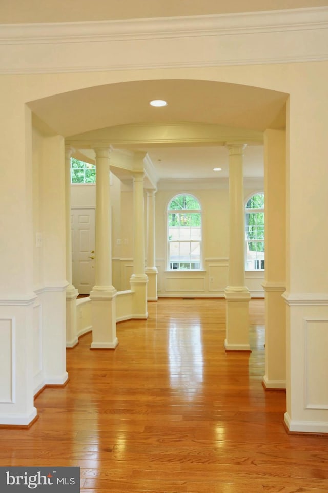 unfurnished room with light wood-style floors, decorative columns, and a decorative wall