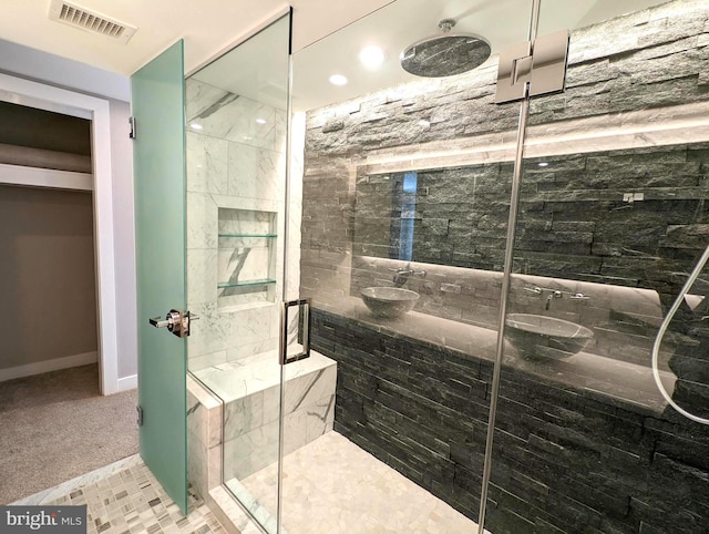 full bath with visible vents, a sink, a shower stall, and baseboards