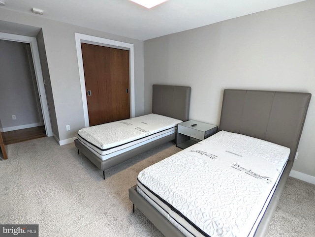 bedroom with light carpet, a closet, and baseboards