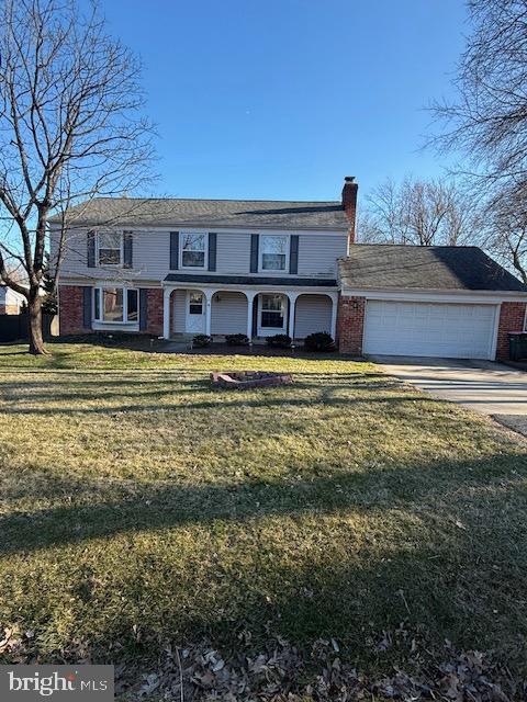 view of front facade featuring a front yard, brick siding, driveway, and a chimney