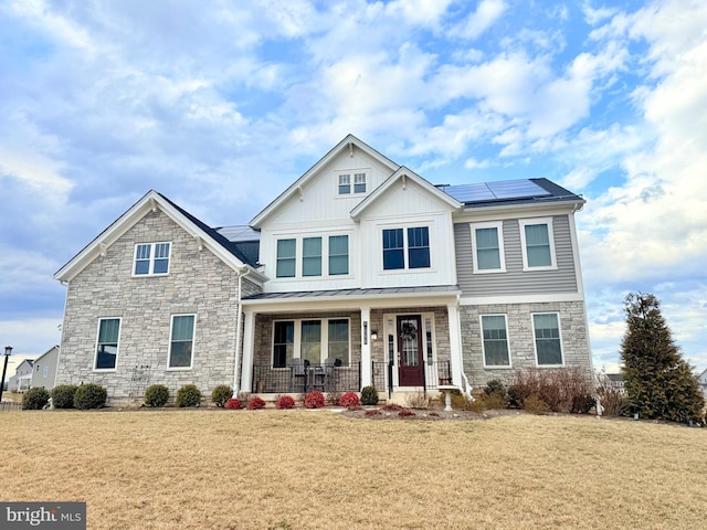 view of front facade featuring solar panels, metal roof, a standing seam roof, a porch, and a front yard