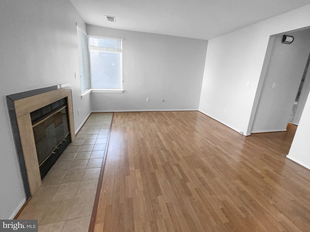 unfurnished living room with light wood-type flooring, a fireplace, and visible vents