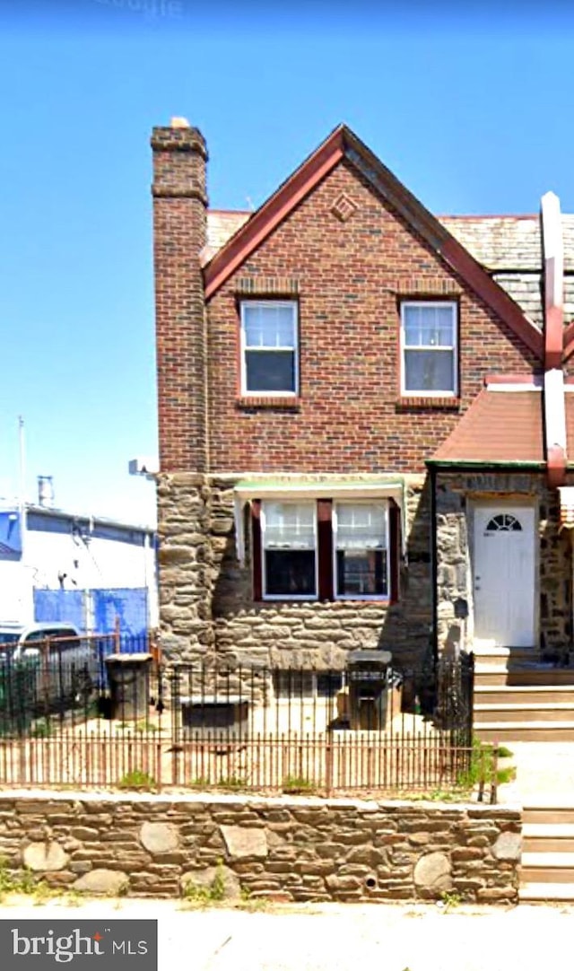 view of front of house featuring a fenced front yard, stone siding, and a chimney