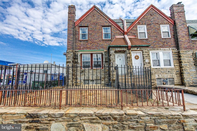 view of front of property featuring a fenced front yard, stone siding, brick siding, and a chimney