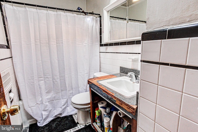 bathroom with toilet, vanity, tile walls, and a shower with shower curtain