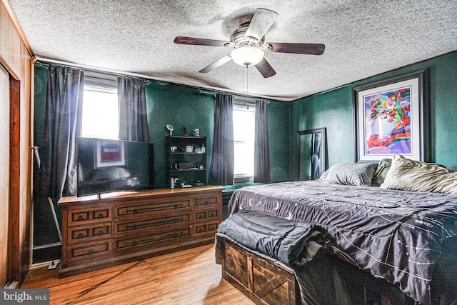 bedroom featuring ceiling fan, a textured ceiling, and wood finished floors