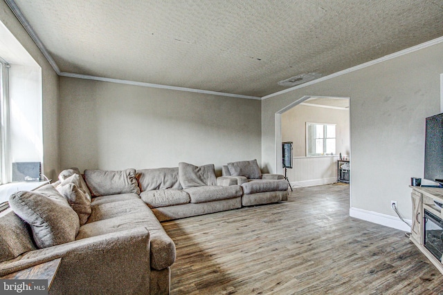 living area featuring baseboards, crown molding, arched walkways, and wood finished floors