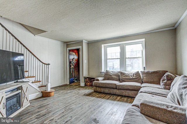 living room with baseboards, ornamental molding, wood finished floors, stairs, and a textured ceiling