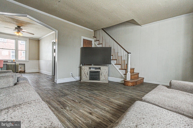 living room with crown molding, wood finished floors, ceiling fan, and stairs