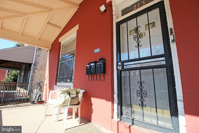 entrance to property with covered porch, brick siding, and concrete block siding