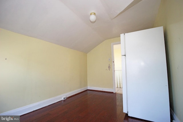 additional living space featuring lofted ceiling, dark wood-type flooring, and baseboards