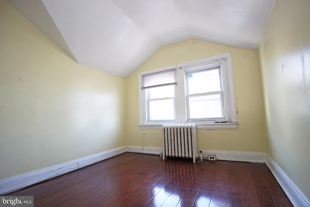 additional living space featuring baseboards, vaulted ceiling, hardwood / wood-style floors, and radiator heating unit