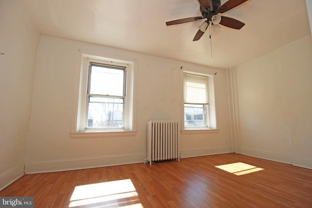 empty room with radiator heating unit, baseboards, and wood finished floors