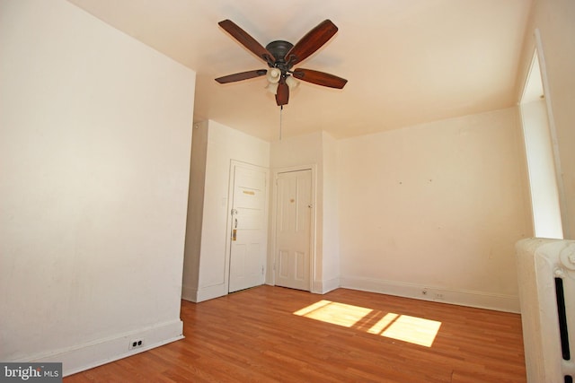 unfurnished room featuring ceiling fan, wood finished floors, and baseboards